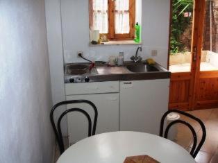 uma cozinha com um lavatório, uma mesa e cadeiras em The Schoolmistress With The Golden Eyes, studios & rooms em Metímna