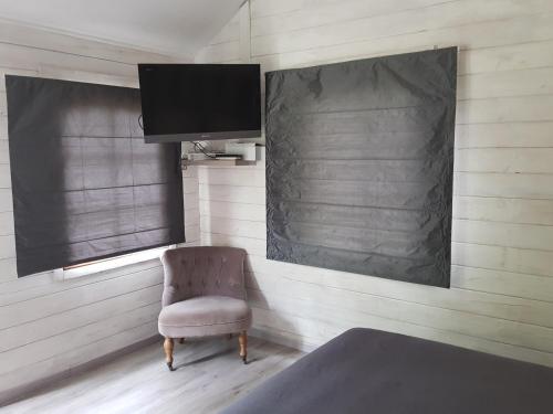 a bedroom with a chair and a flat screen tv at La cabane de Pioupiou in Fayence