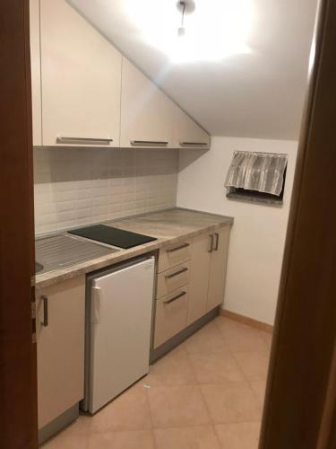 a kitchen with white cabinets and a stove top oven at Apartman MIG in Solin