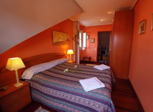 1 dormitorio con 1 cama grande y pared de color naranja en Chalet Argoños, en Argoños
