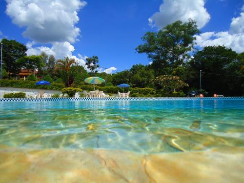 a swimming pool with chairs and umbrellas in the water at Hotel Pontal de Tiradentes in Tiradentes