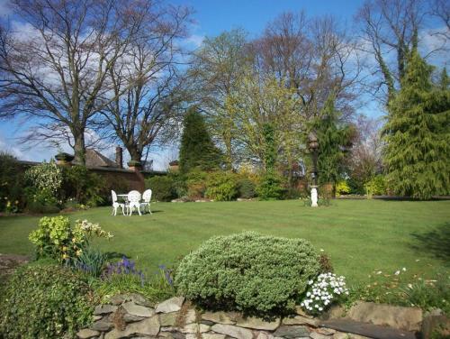 a yard with two white chairs in the grass at The Cedars Ashby in Ashby de la Zouch