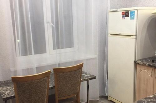 a kitchen with a table with two chairs and a refrigerator at Apartment on Dzerzhinskogo 62 in Tyumen
