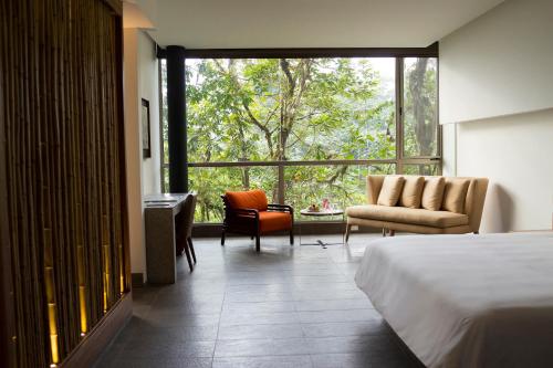 a bedroom with a bed and a chair and a window at Mashpi Lodge in Pacto