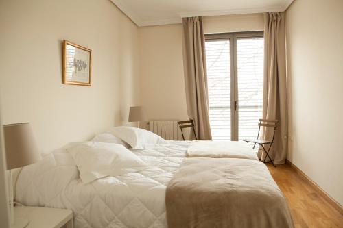 a white bedroom with a large bed and a window at Piso en el Centro Plaza de España in Seville