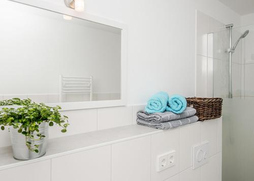 a white bathroom with a shelf with towels and a mirror at Spreewaldapartments-Kossatz in Lübben