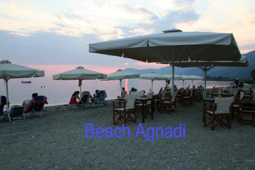 people sitting in chairs under umbrellas on a beach at Agnadi Hotel in Rovies