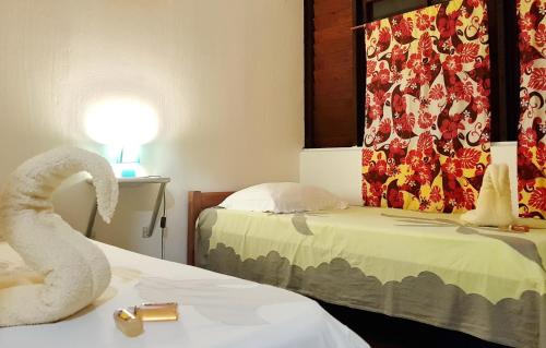 a hotel room with two beds and a towel on a table at Pension Les Trois Cascades in Uturoa