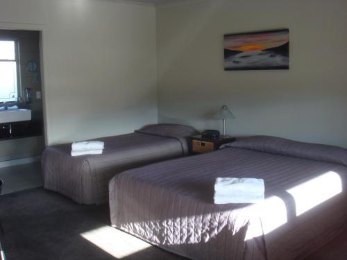 a hotel room with two beds and a window at Bristol Motel in Upper Hutt