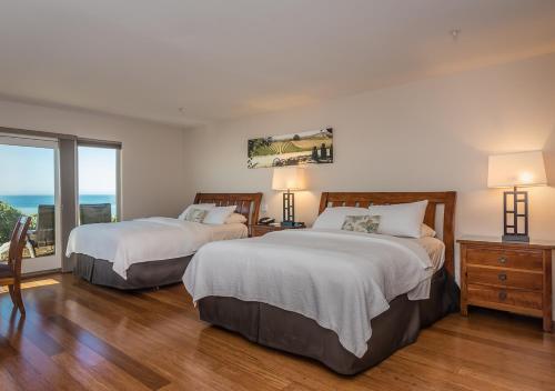 a bedroom with two beds and a large window at Little Sur Inn in Cambria