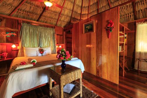a bedroom with a bed and a table with flowers on it at St. George's Caye Resort in Belize City