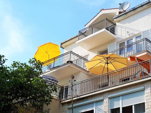 two yellow umbrellas on the balconies of a building at Apartments T&M in Vinišće