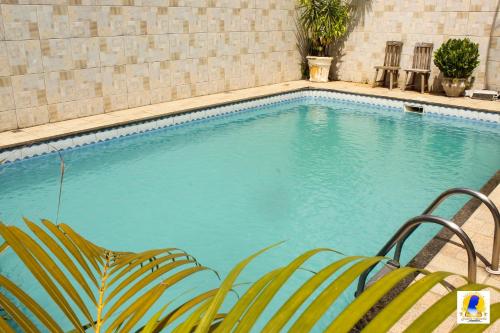 a swimming pool with two chairs in front of it at Pousada Santa Maria in Aparecida