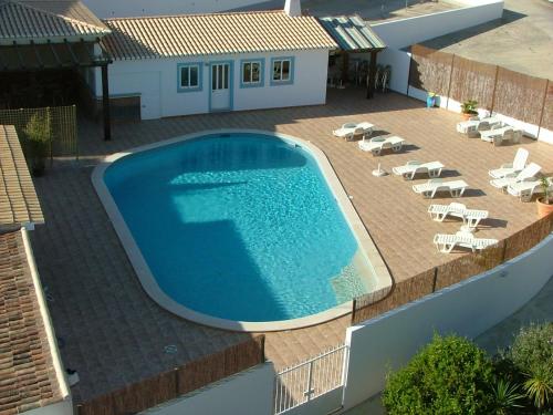 
a large white swimming pool sitting next to a house at Hotel Burgau Turismo de Natureza in Burgau
