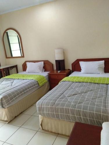 a bedroom with two beds and a mirror at Villa bora-bora Kalicaa in Tanjung Lesung