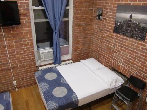 a bed in a brick room with a window at Studios Midtown Manhattan in New York