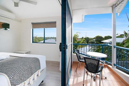 a bedroom with a balcony with a bed and a table at Gosamara Apartments in Byron Bay