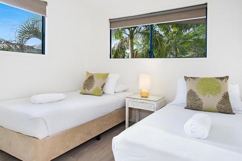 two beds in a room with two windows at Gosamara Apartments in Byron Bay
