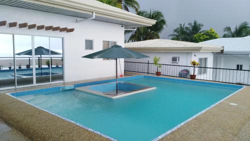 a swimming pool with an umbrella in front of a house at Seaview Mansion Dalaguete Apartment 3 in Dalaguete