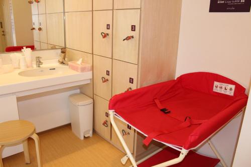 Una silla roja en el baño con lavabo en Tomakomai Hotel Sugita en Tomakomai