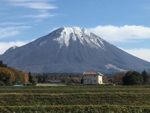a snow covered mountain with a house in a field at Lodge Sano in Daisen