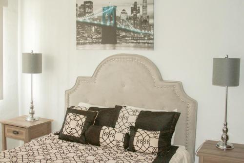 a bed with black and white pillows and two lamps at 2 BEDROOM / 1 BATH ONLY 5 MINUTES AWAY FROM BANK OF HAWAII in Sinajana