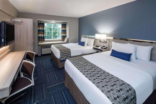 a hotel room with two beds and a flat screen tv at Microtel Inn & Suites - Greenville in Greenville