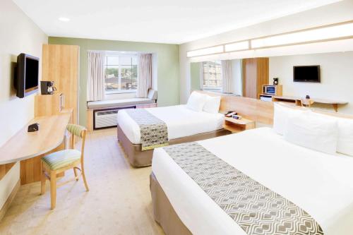 a hotel room with two beds and a desk at Microtel Inn & Suites by Wyndham Saraland in Saraland