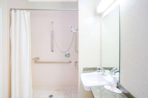 a white bathroom with a shower and a sink at Microtel Inn & Suites by Wyndham Saraland in Saraland
