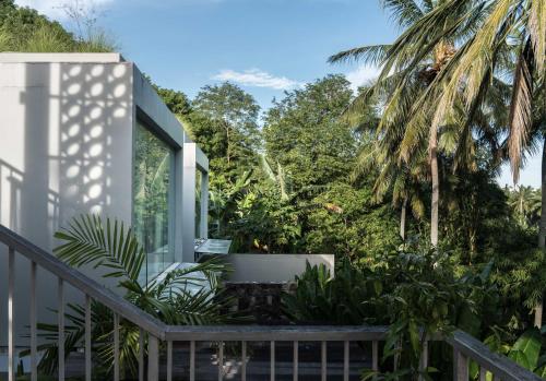 a house with a balcony with palm trees at Svarga Resort Lombok in Senggigi 