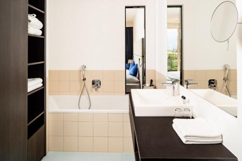 a bathroom with a sink and a bath tub at Hotel Thalhof am See in Caldaro