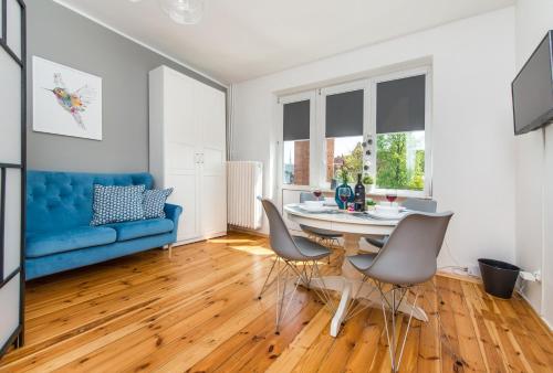 ein Wohnzimmer mit einem blauen Sofa, einem Tisch und Stühlen in der Unterkunft Baszta Jacek Gdańsk in Danzig