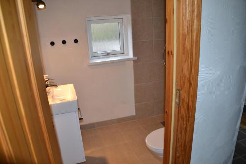 a bathroom with a toilet and a sink and a window at Markvænget 5 in Sønder Felding