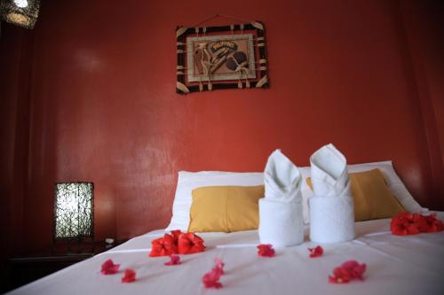 a bed with white towels and red flowers on it at Discovery Island Resort in Coron