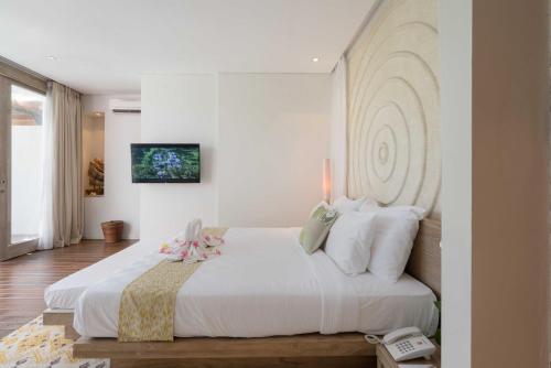 a bedroom with a large white bed with white walls at Svarga Resort Lombok in Senggigi 