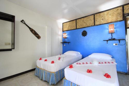 a room with two beds with red flowers on them at Discovery Island Resort in Coron