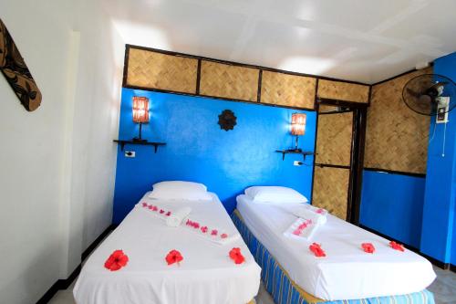 two twin beds in a room with blue walls at Discovery Island Resort in Coron