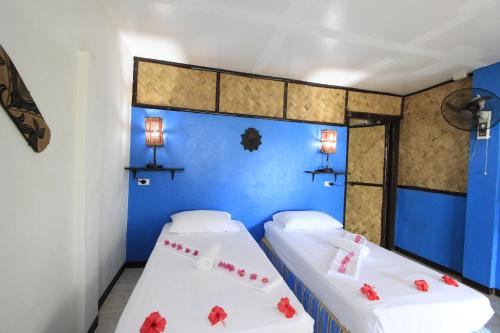 two beds in a room with blue walls and red flowers at Discovery Island Resort in Coron