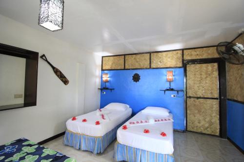 a room with two beds and a blue wall at Discovery Island Resort in Coron