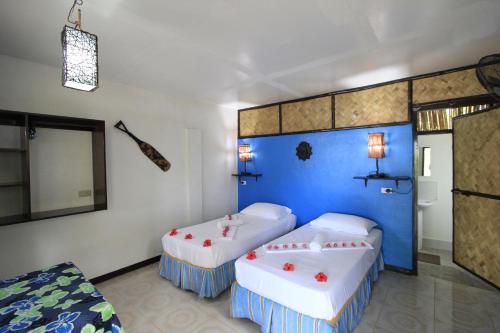 a bedroom with two beds and a blue wall at Discovery Island Resort in Coron