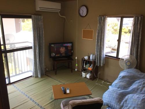a living room with a tv and a table at Guesthouse Suisennosato in Konan
