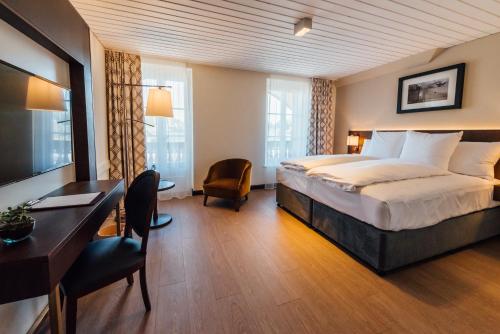 ein Hotelzimmer mit einem Bett und einem Schreibtisch in der Unterkunft Hotel Taverna in Tafers