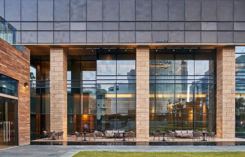 a large glass building with tables and chairs in it at The Den, Bengaluru in Bengaluru