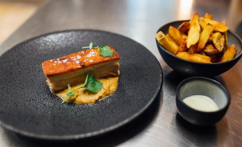 a black plate with a piece of food and french fries at Hotel Taverna in Tafers