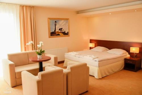 ein Hotelzimmer mit einem Bett und einem Stuhl in der Unterkunft Król Plaza Spa & Wellness in Jarosławiec