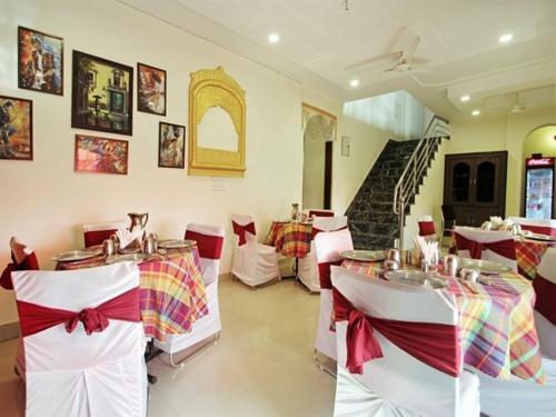 a restaurant with white tables and red and white chairs at Taj Haveli Agra - 5 Minute Walking Distance from Taj Mahal Agra in Agra