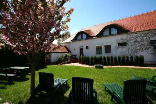 a house with chairs and a tree in the yard at Tornácos Hotel - Hegykő in Hegykő