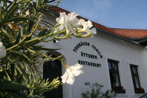 a building with white flowers in front of it at Tornácos Hotel - Hegykő in Hegykő