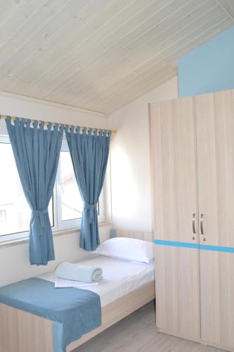 a bedroom with a bed with blue curtains at Open Doors Bed & Breakfast in Shkodër