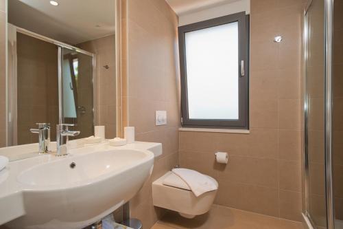 a bathroom with a sink and a toilet and a window at Villa Paulina in Brela